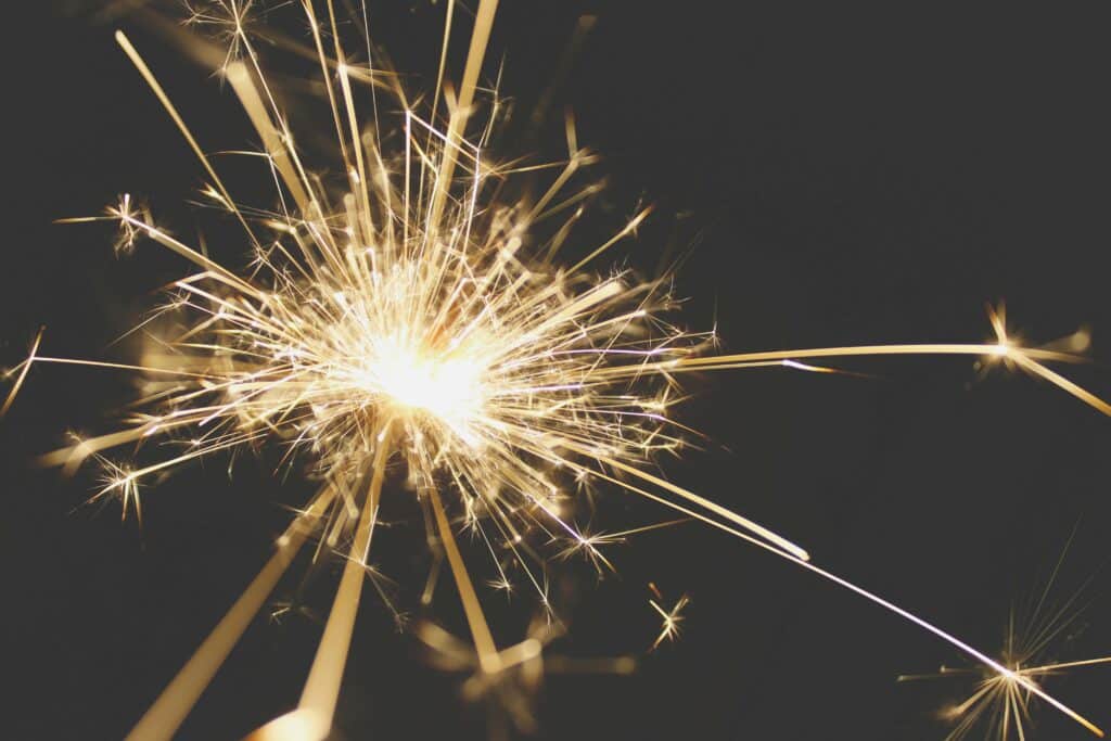 Close-up of a dazzling sparkler bursting with light against a dark background, perfect for celebrations.