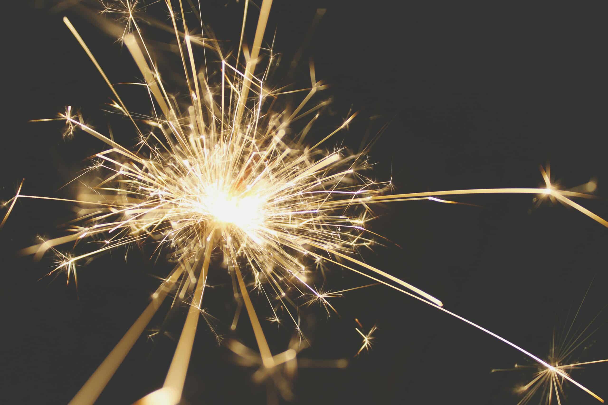 Close-up of a dazzling sparkler bursting with light against a dark background, perfect for celebrations.