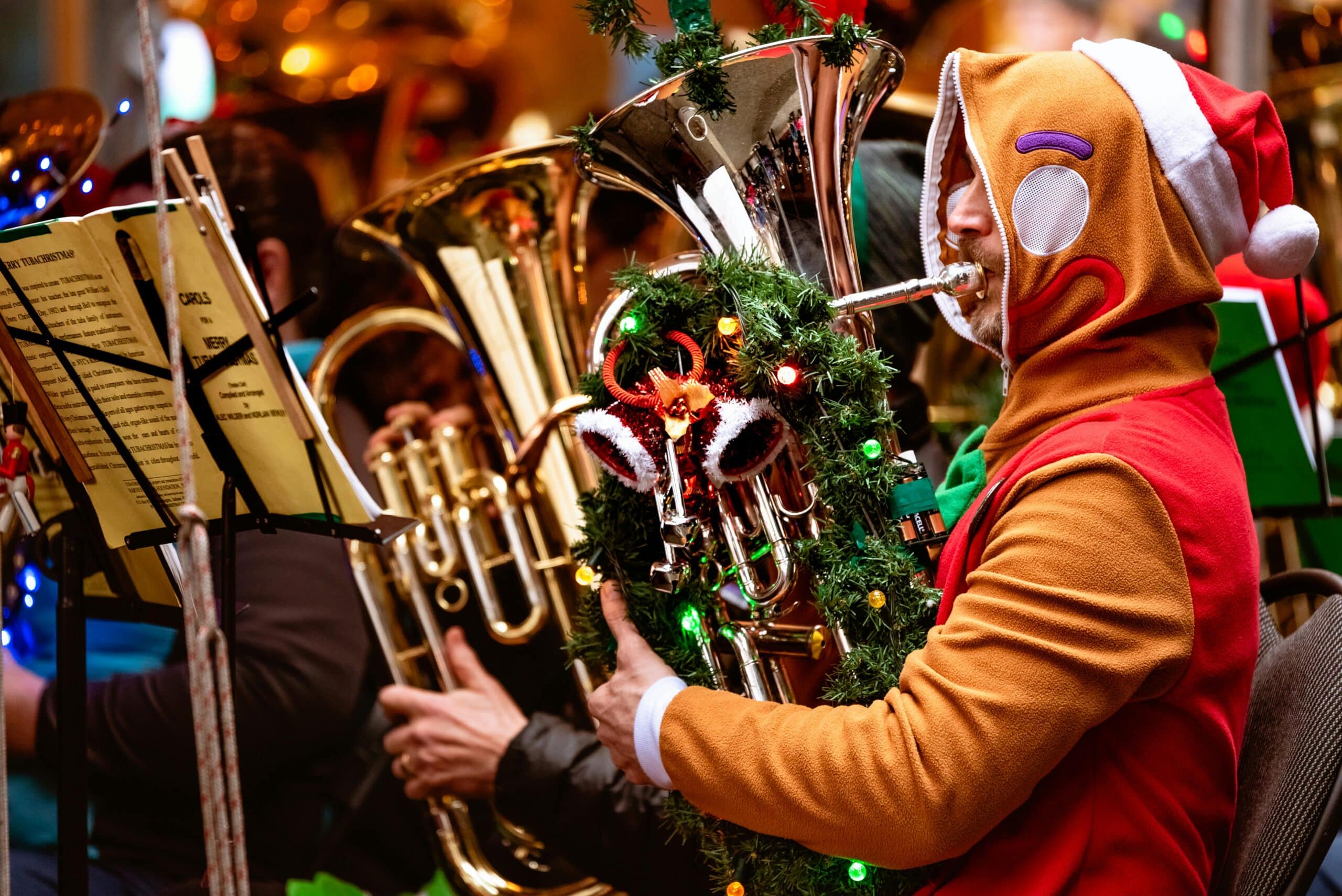 Colorful Christmas band performance featuring a musician in a gingerbread costume playing the tuba.