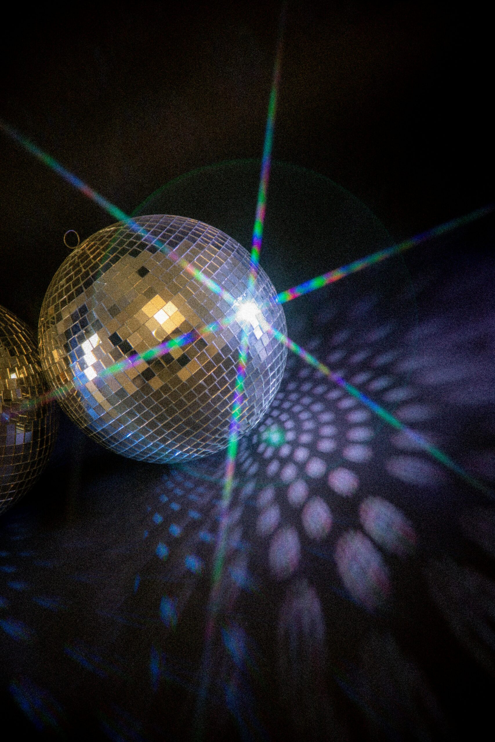 Captivating image of a disco ball casting rainbow light patterns against a dark background, creating an enchanting atmosphere.