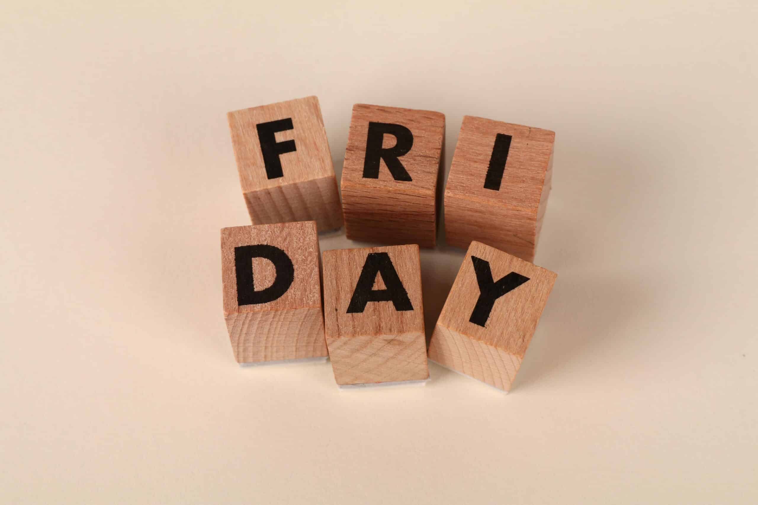 Wooden cubes spelling 'Friday' on a neutral surface with copy space.