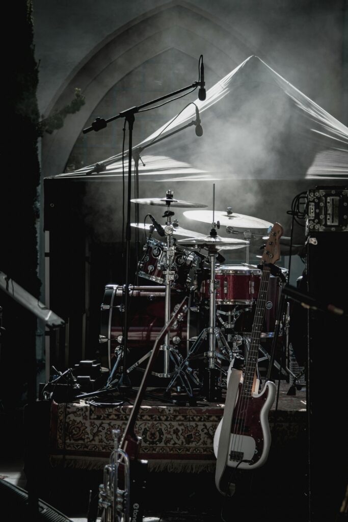 Dimly lit stage with drum kit and electric guitar ready for a live performance.