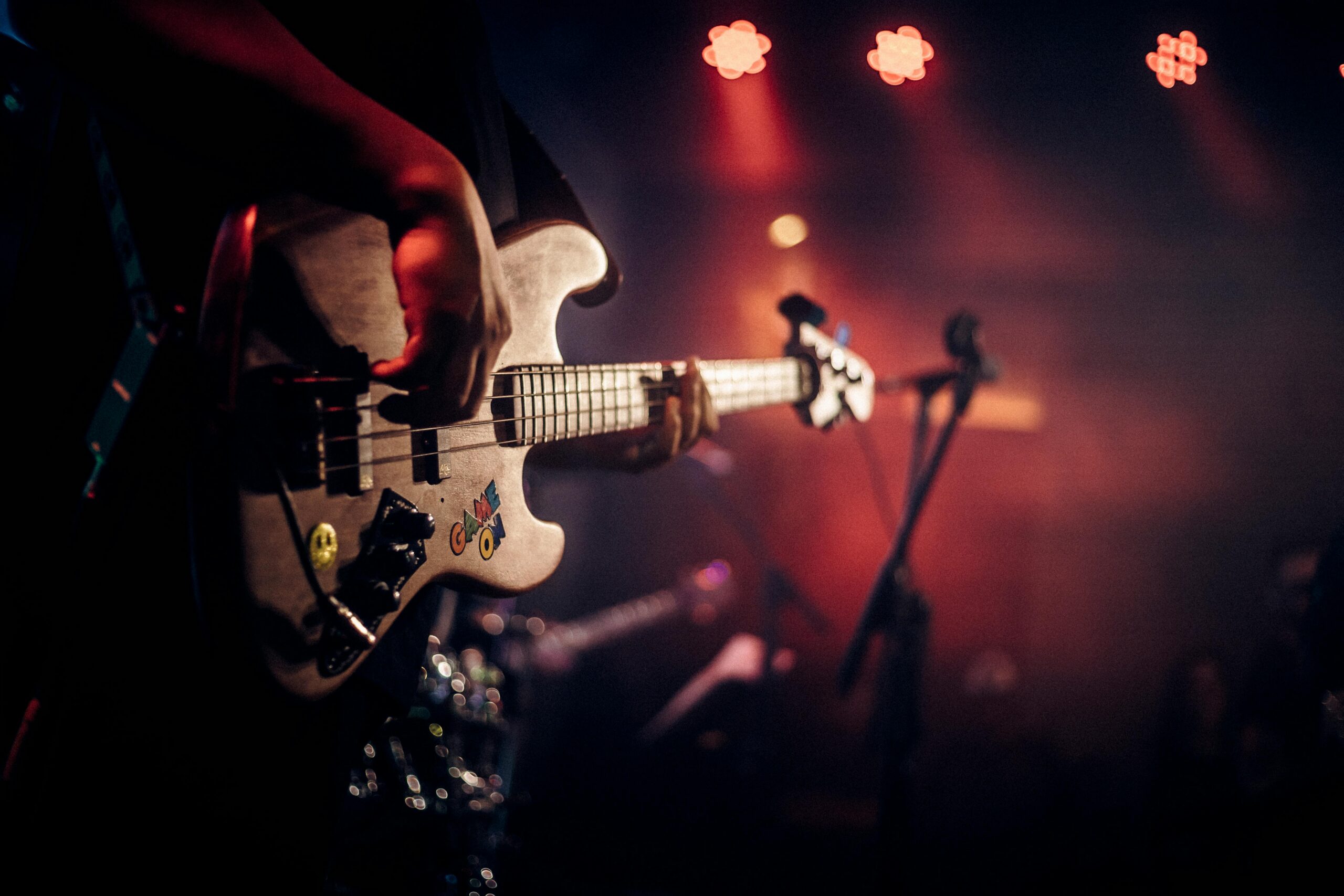 Dynamic image of a guitarist playing at a live music concert, illuminated by colorful stage lights.