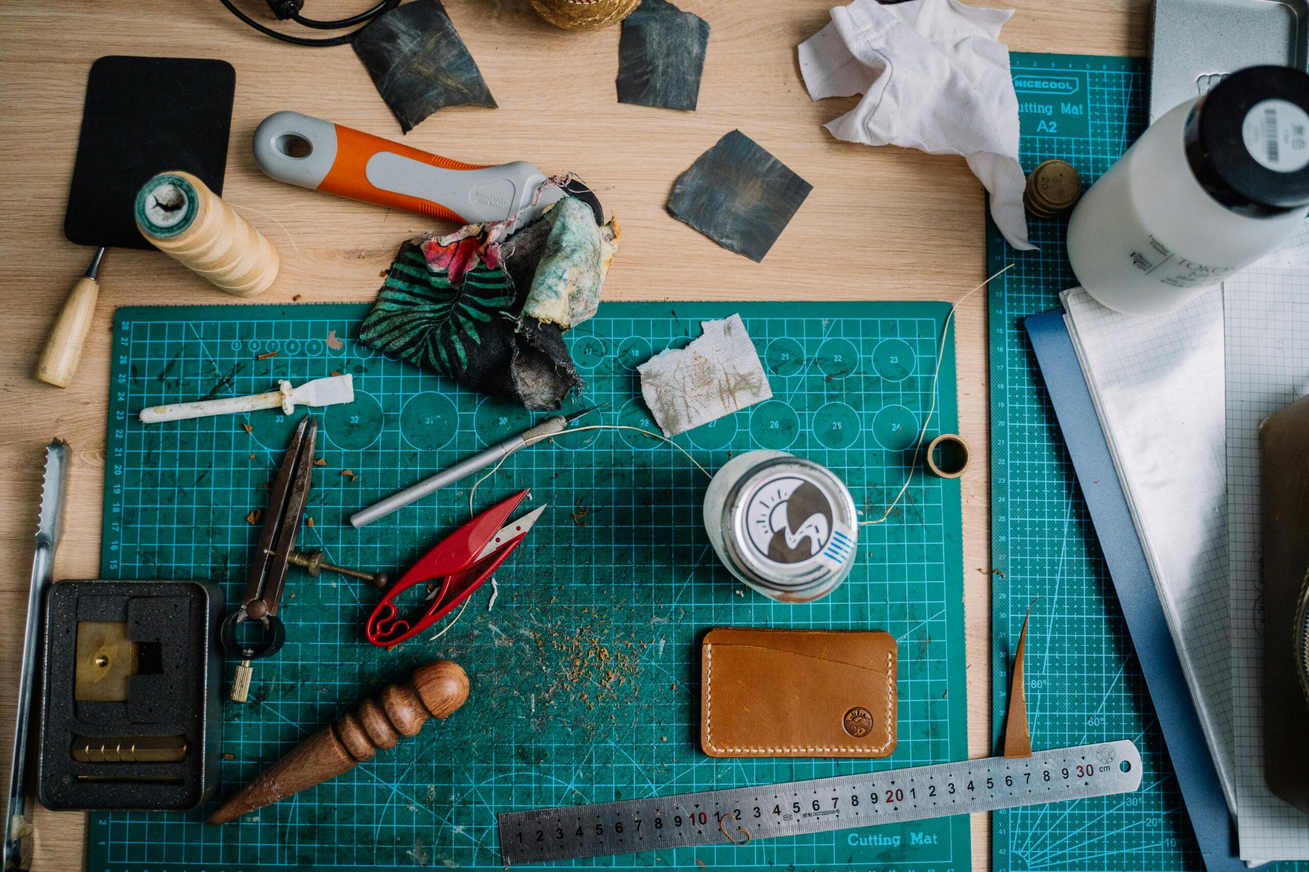 Top view of a leather crafting workstation with tools and materials on a cutting mat.